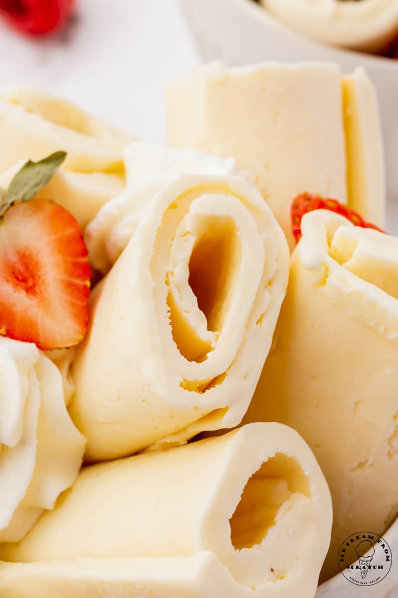 Closeup view of homemade rolled ice cream. It's vanilla flavored, and garnished with fresh strawberries.