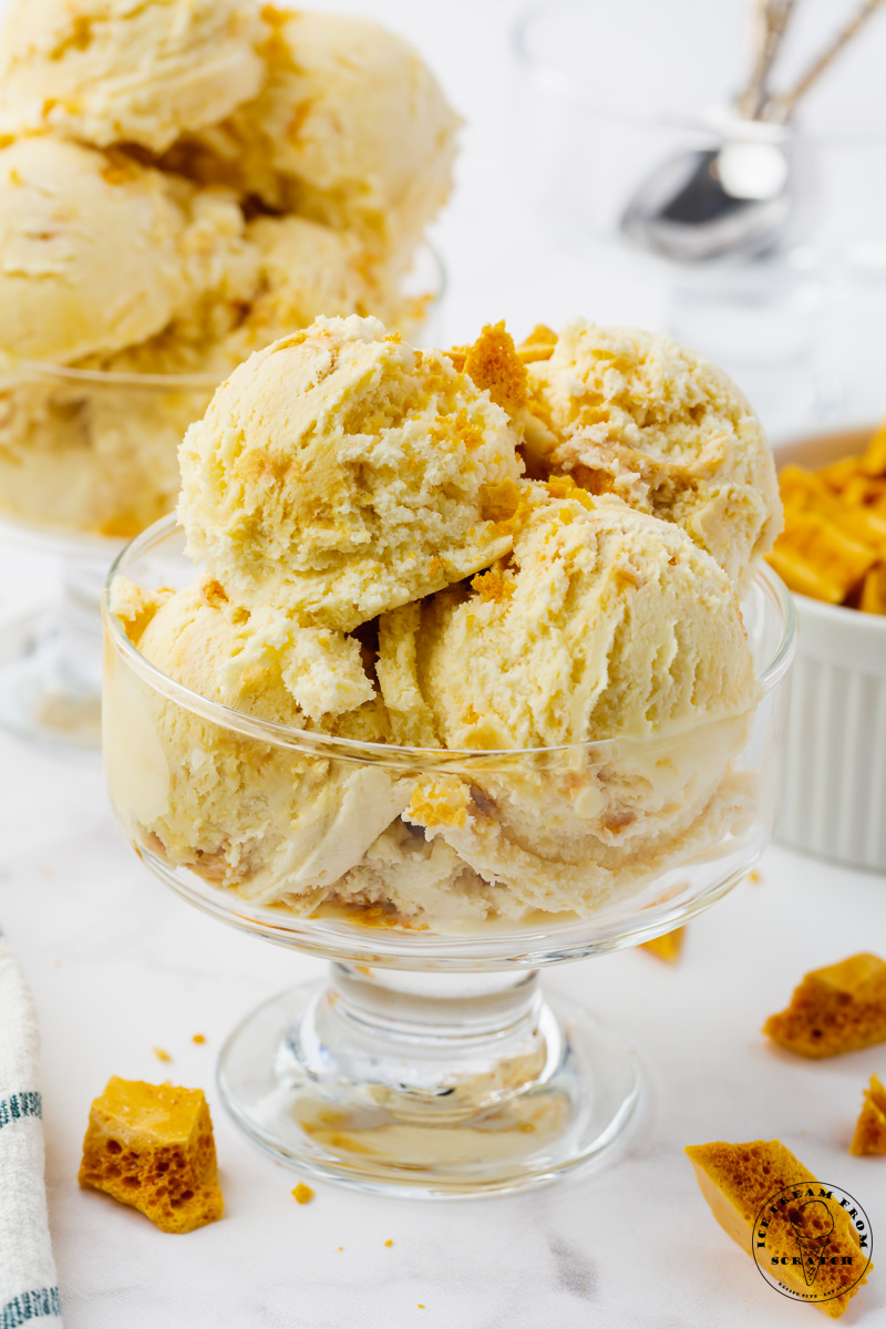 homemade ice cream with honeycomb toffee pieces, scooped into a footed glass ice cream dish.
