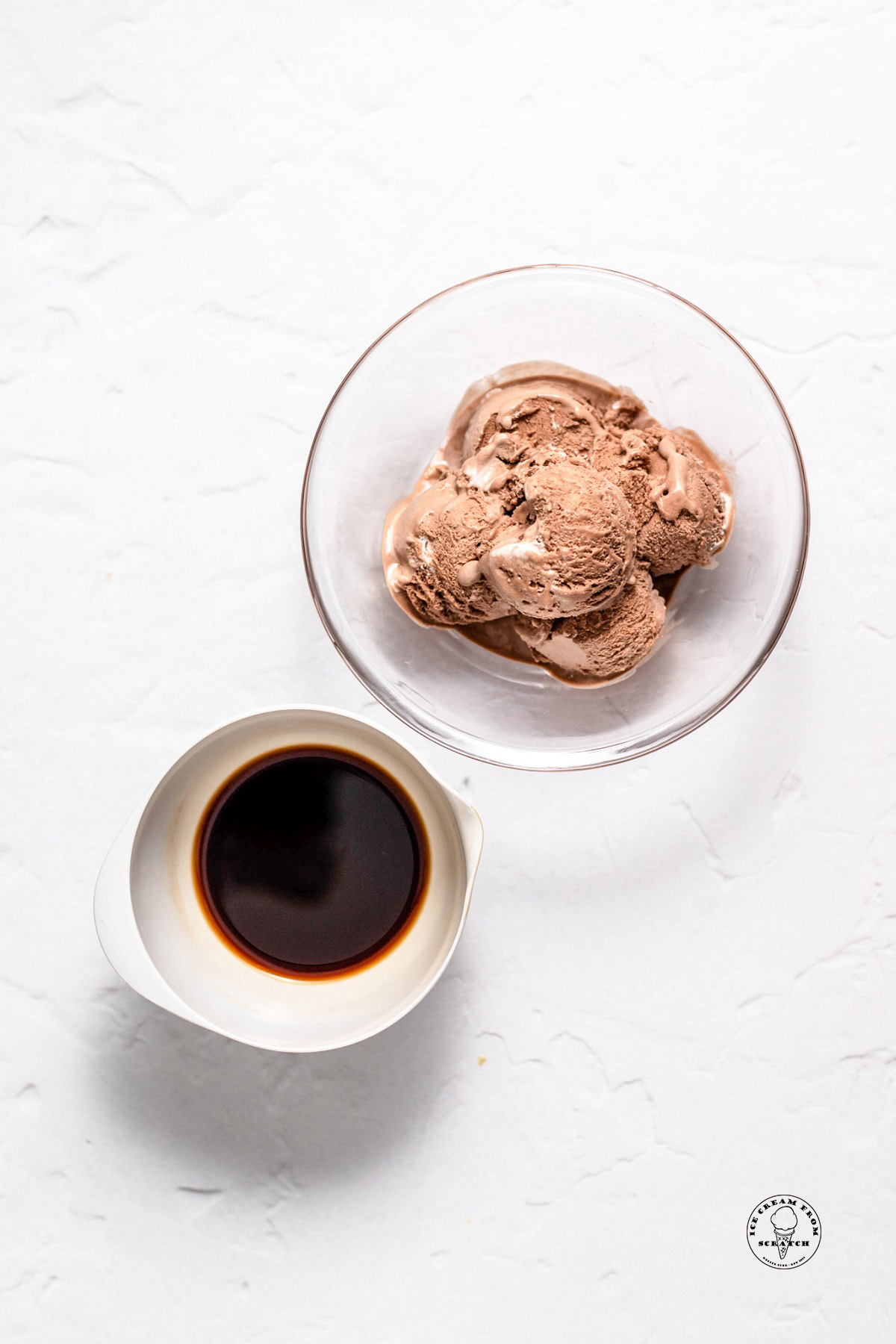A clear glass bowl of chocolate ice cream, and a small white bowl of dark coffee.
