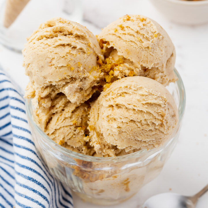 a glass bowl filled with scooops of cookie butter ice cream and crumbled speculaas cookies.