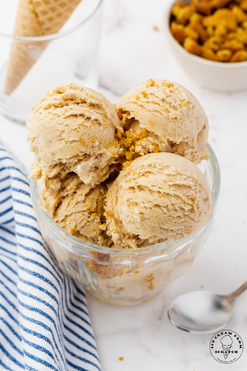 a glass bowl filled with scooops of cookie butter ice cream and crumbled speculaas cookies.