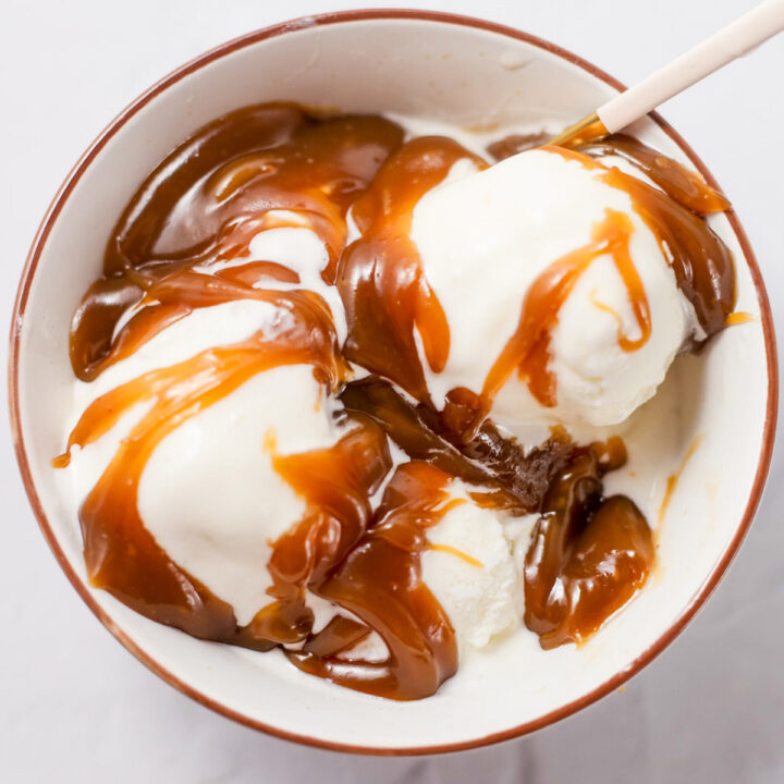 A bowl of vanilla ice cream topped with homemade peanut butter sauce.