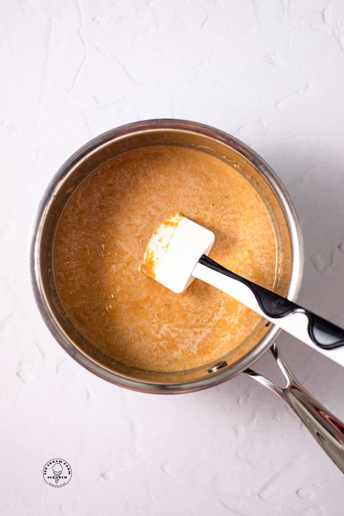 a small saucepan holding ingredients to make peanut butter sauce and a spatula.