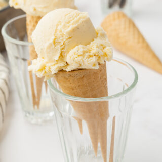 two clear glasses holding cones of custard ice cream.