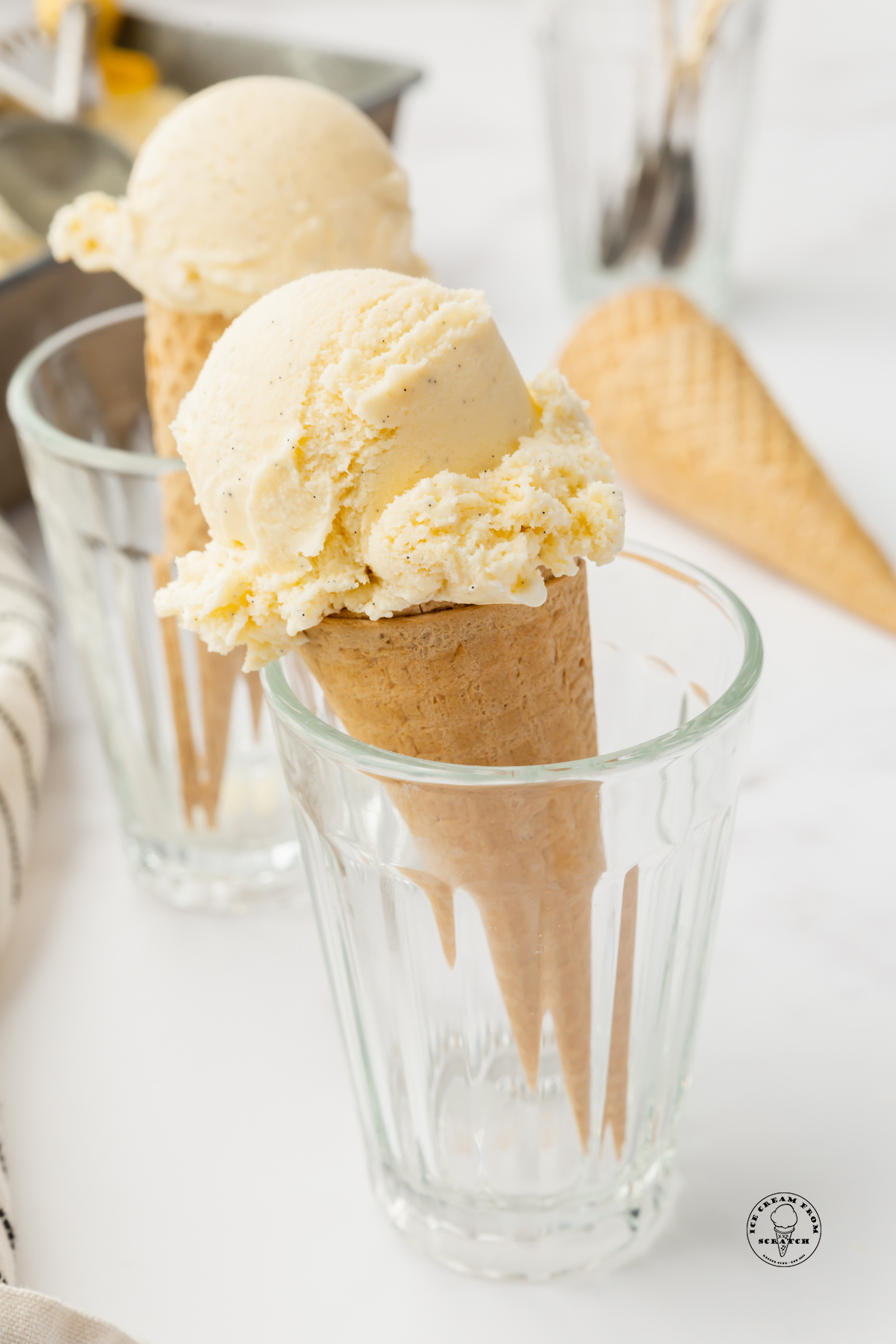 two clear glasses holding cones of custard ice cream.