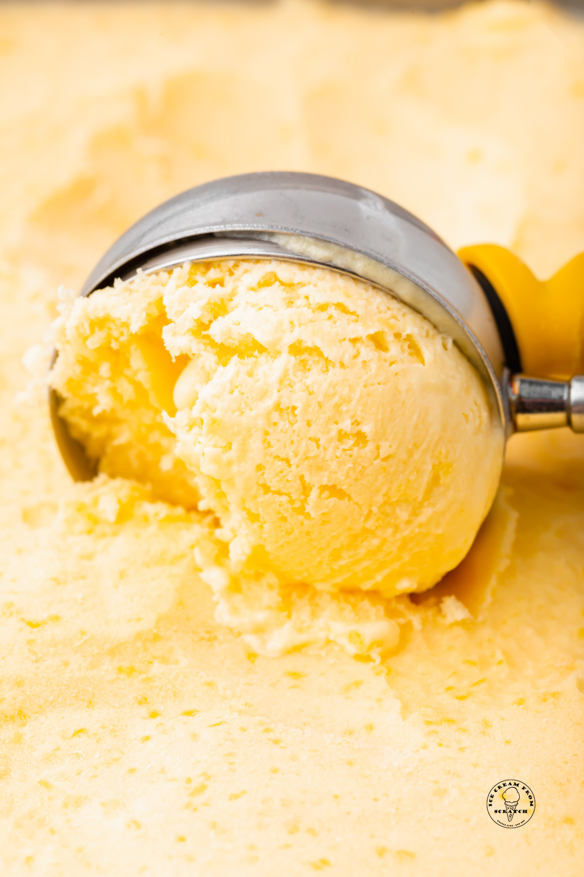 an ice cream scoop pulling through mango gelato, close up shot.