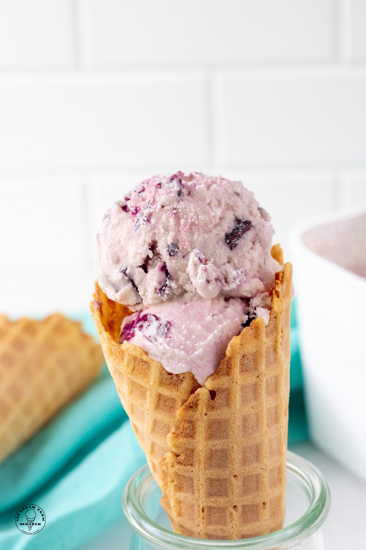 scoops of amaretto ice cream with cherries and chocolate in a waffle cone.