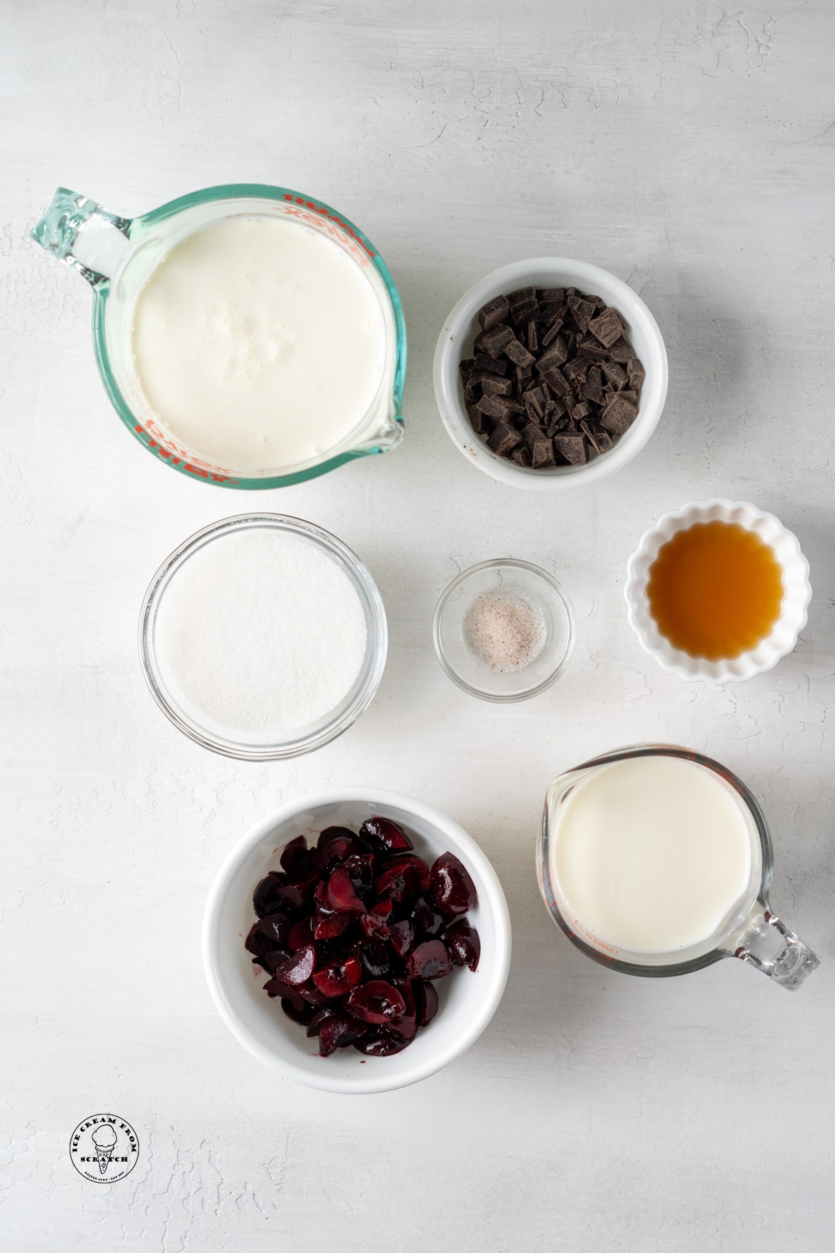The ingredients needed to make amaretto ice cream recipe, including cherries and chocolate chunks. Each ingredient is measured into a bowl.