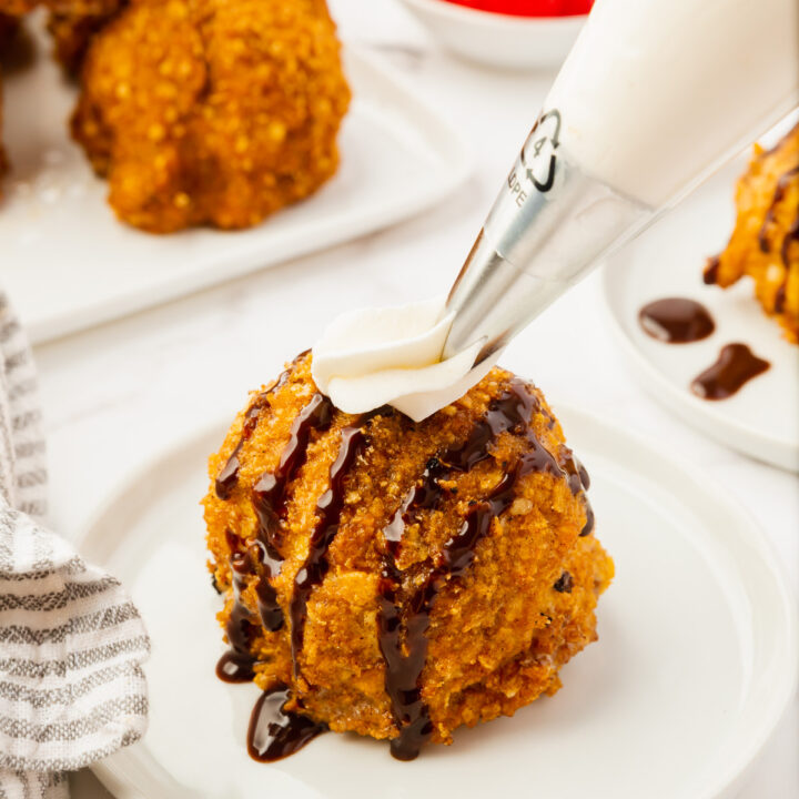 a round serving of fried mexican ice cream topped with chocolate syrup and whipped cream.