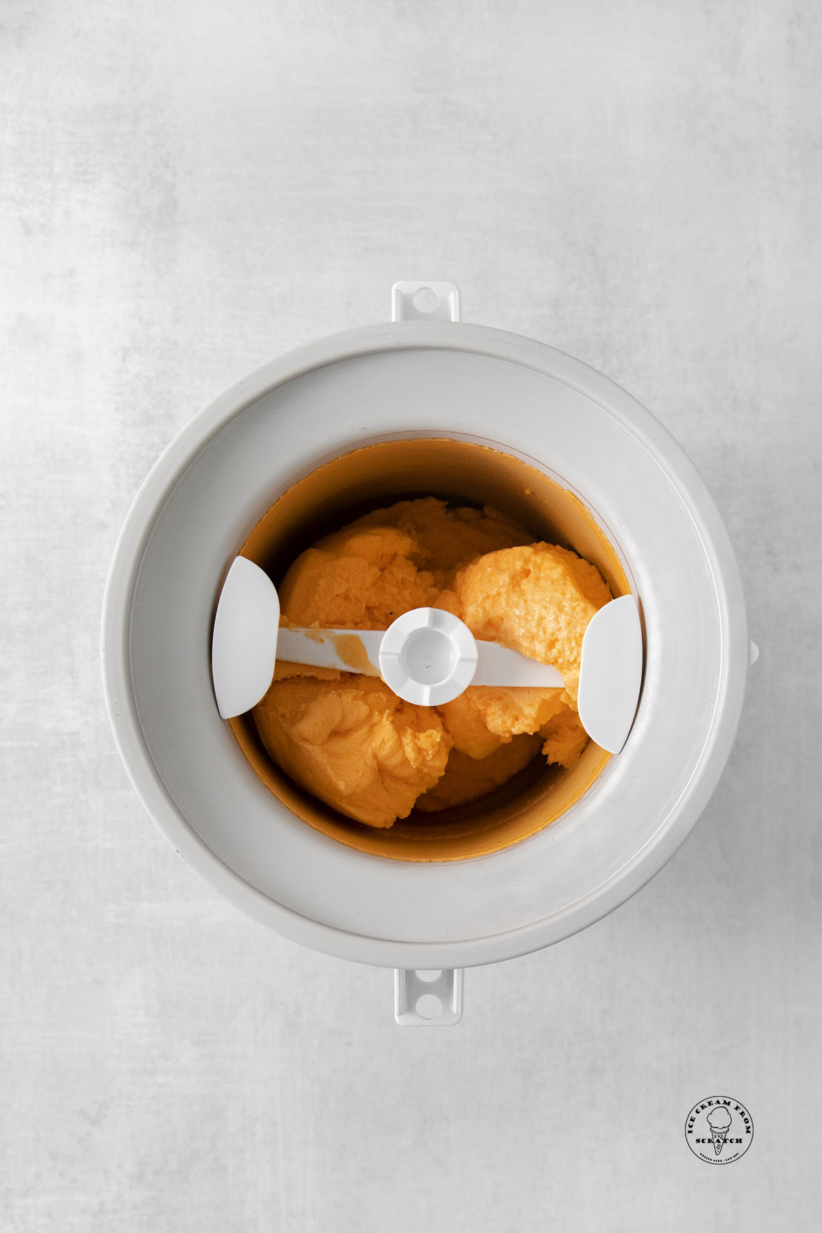 orange sherbet churning in an electric ice cream maker.