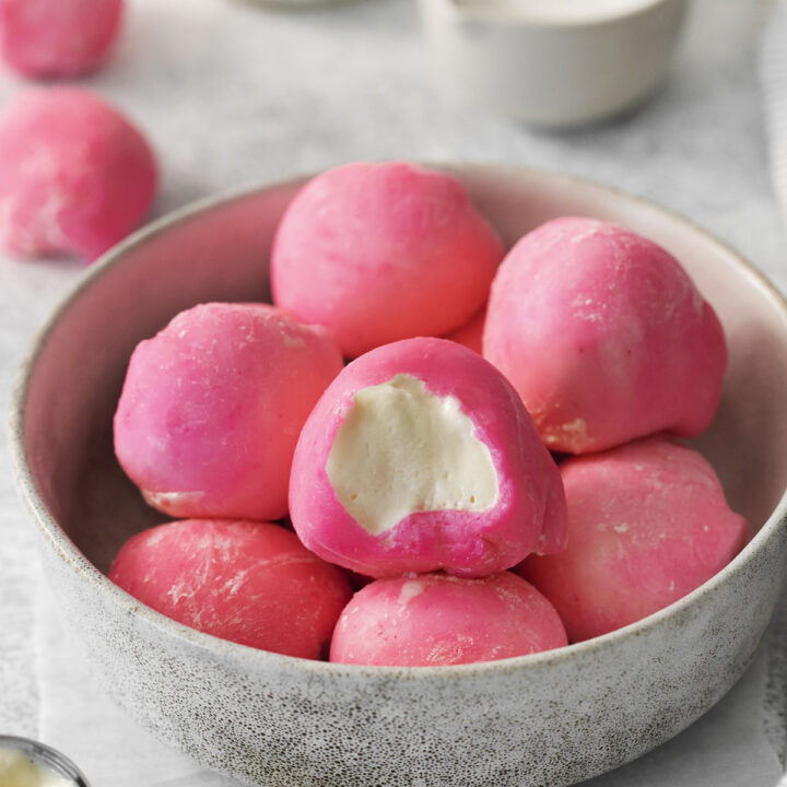 a bowl of homemade mochi with pink topping, filled with vanilla ice cream.