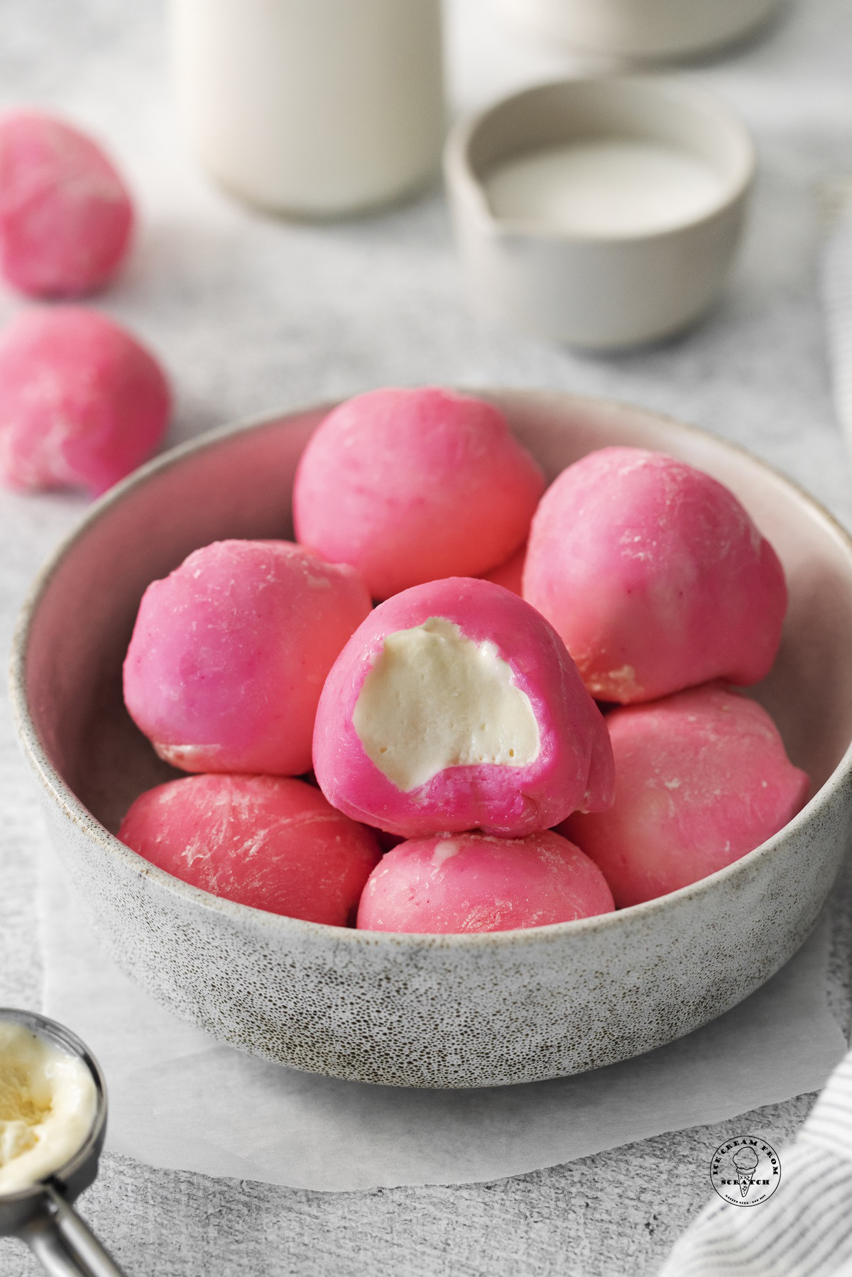 a bowl of homemade mochi with pink coating, filled with vanilla ice cream.