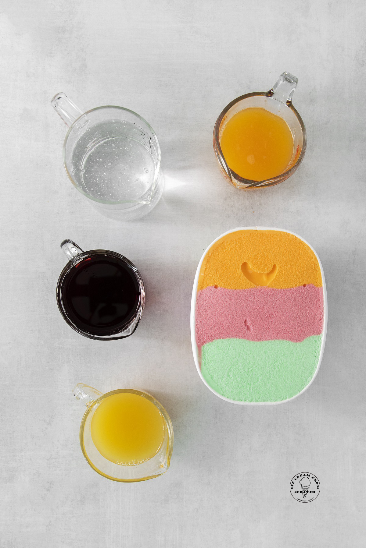The ingredients for the sherbet punch, including juice, soda, and rainbow sherbet, arranged on a counter and viewed from above.