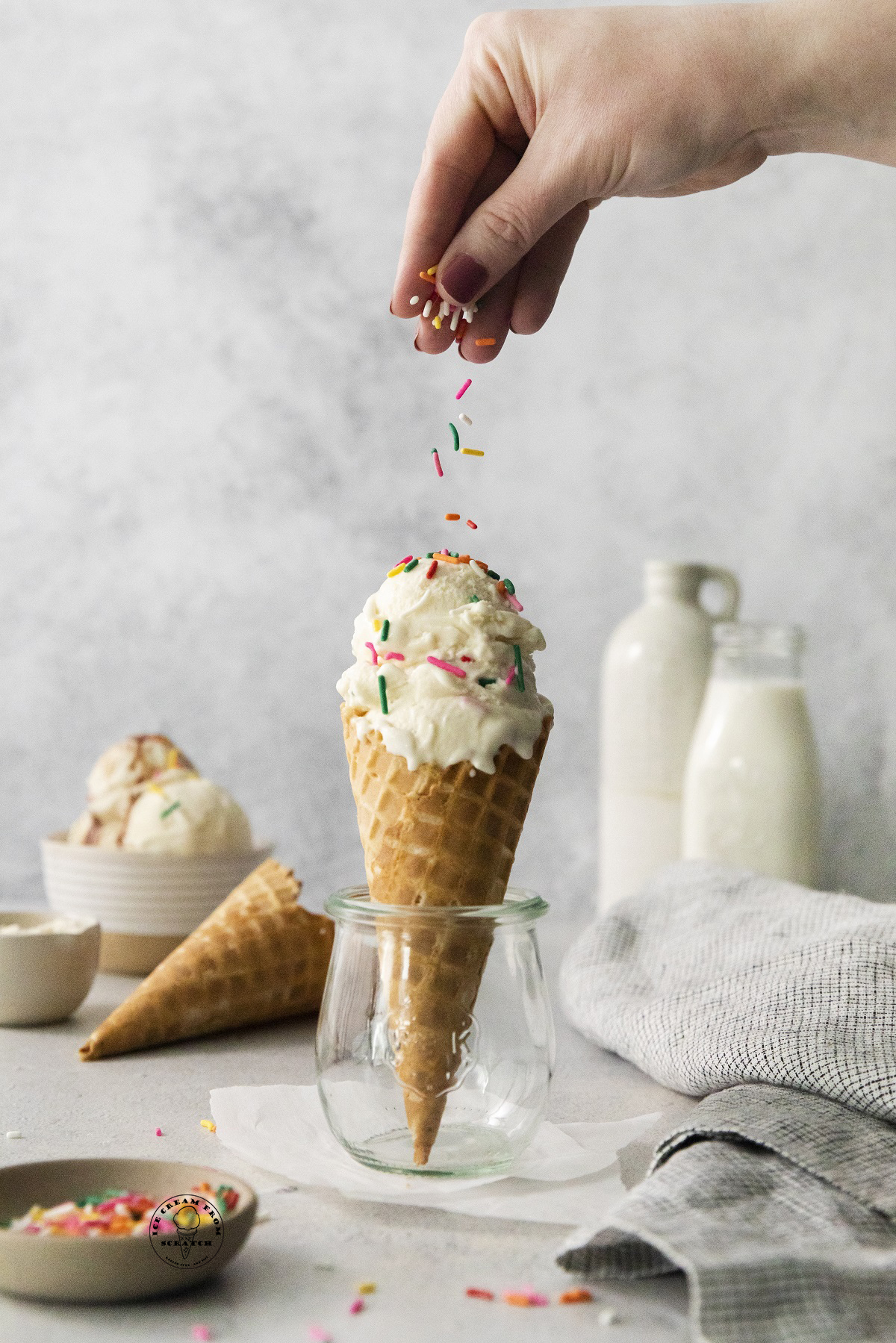 a hand sprinkling sprinkles over a cone of anabolic ice cream