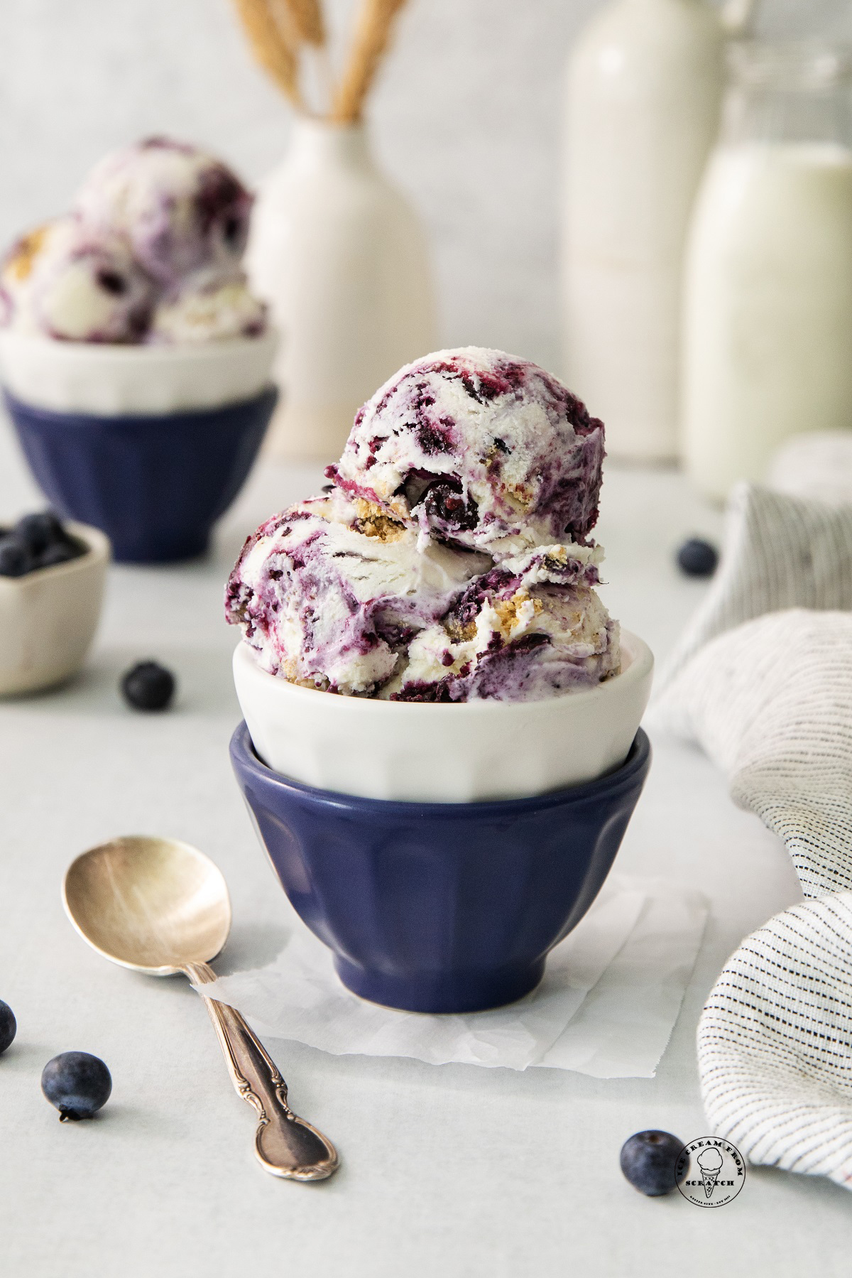 scoops of blueberry cheesecake ice cream in a blue ceramic bowl.