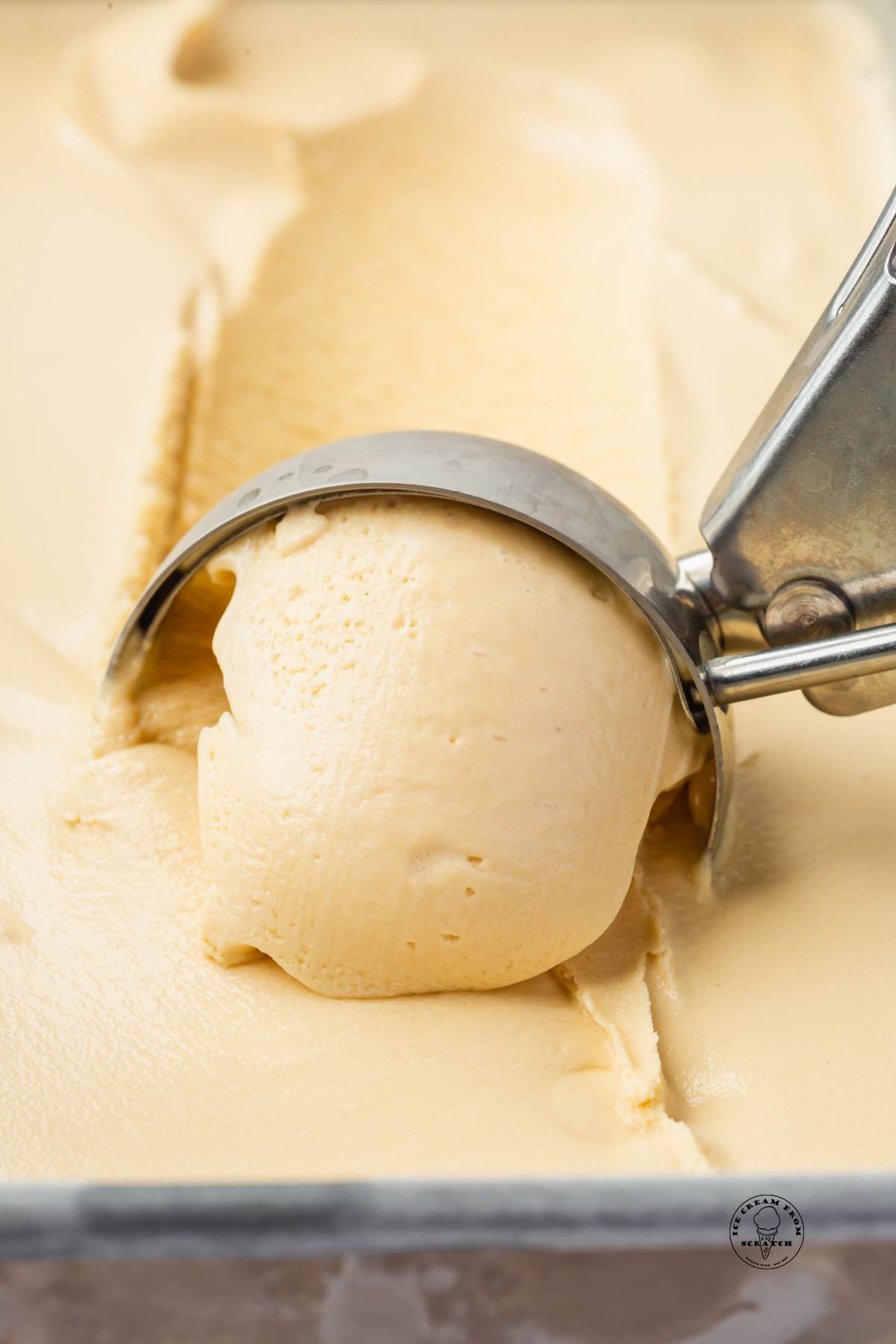 a metal scoop pulling a scoop of homemade creamy caramel ice cream.