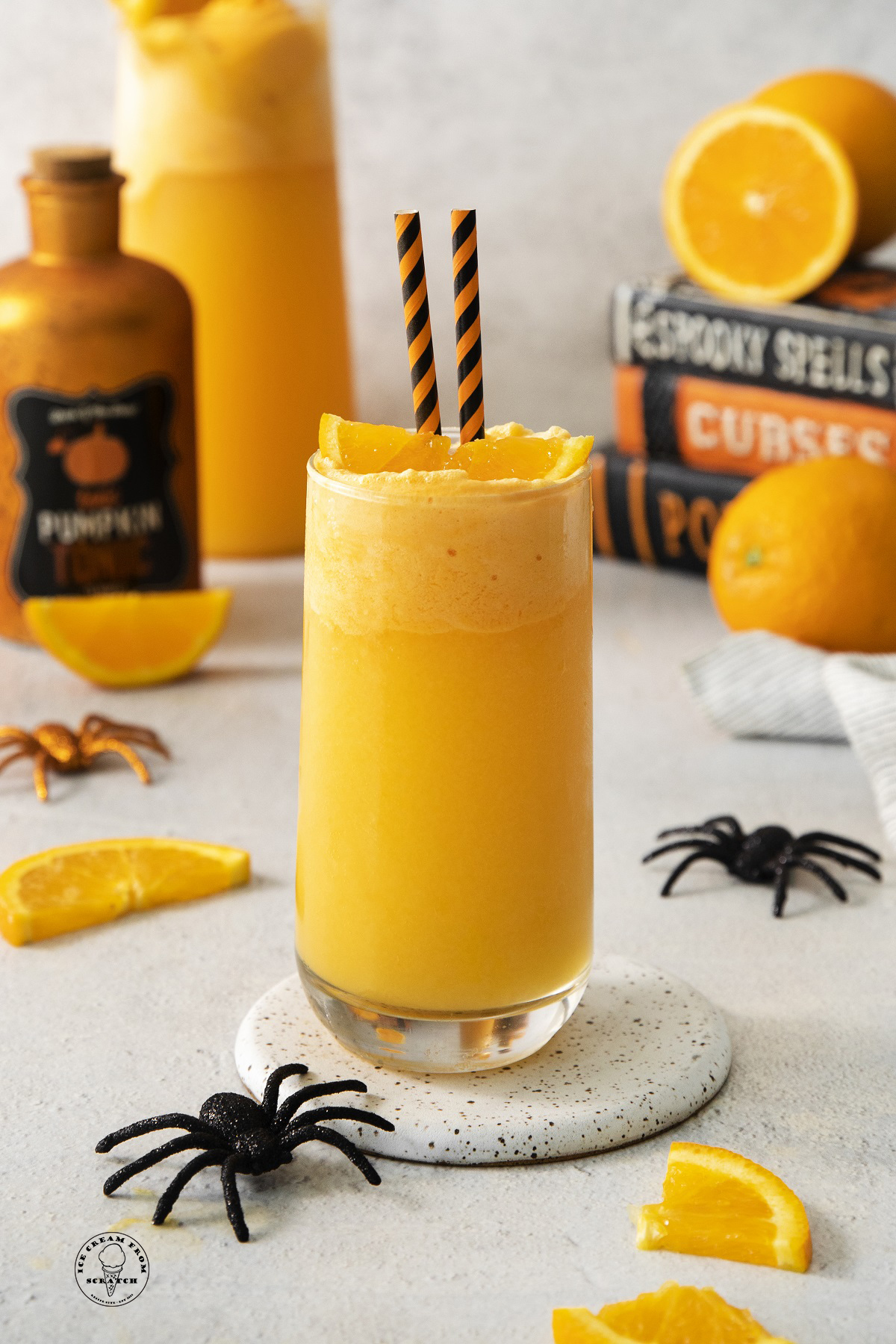 Orange halloween punch in a glass. Halloween decorations are in the background.