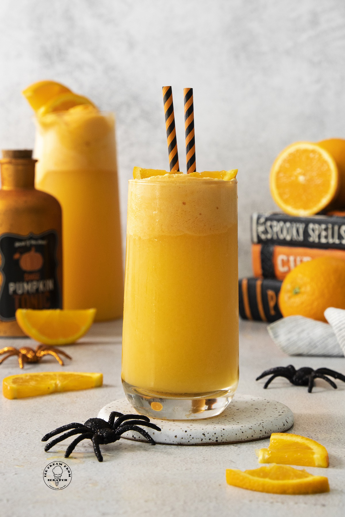 a tall glass filled with orange punch topped with orange sherbet and an orange slice.