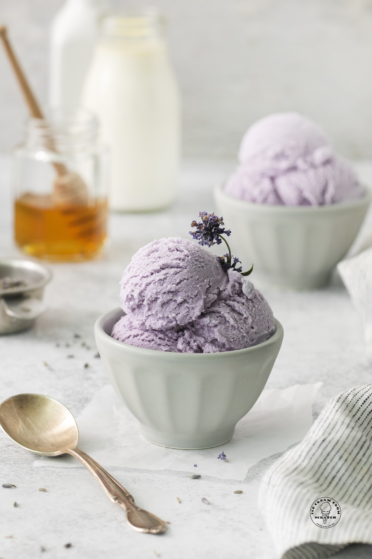 a small dish of scoops of lavender ice cream with flowers as garnish.