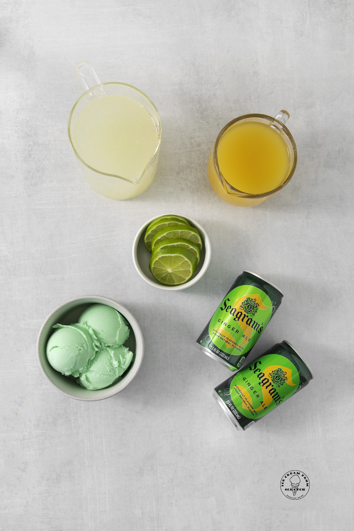 two cans of seagrams ginger ale on a counter with a bowl of lime sherbet, lime wedges, and juice for punch.