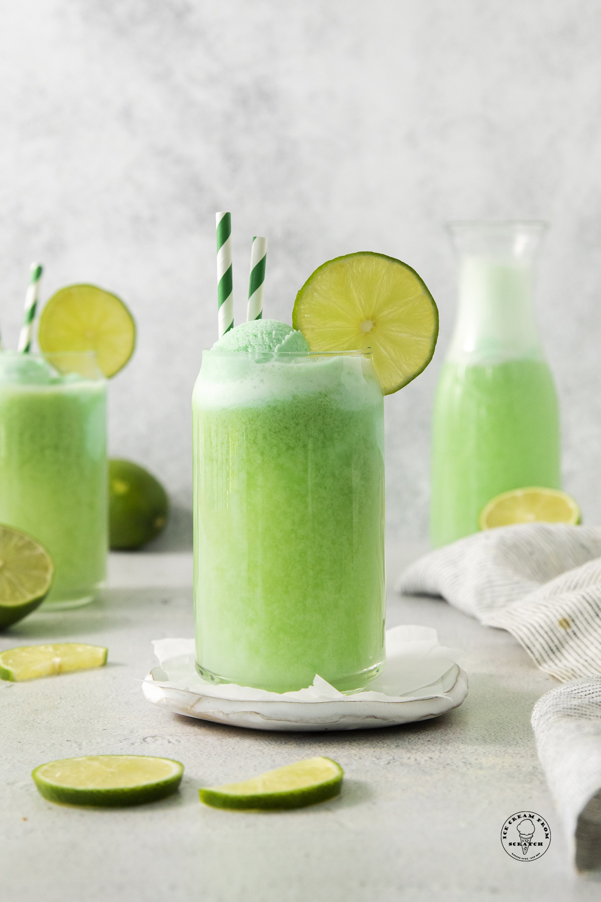 a clear glass of green punch with lime sherbet and lime wedges.