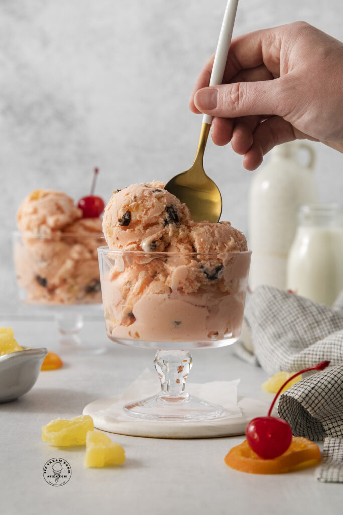 a hand holding a gold toned spoon in a dish of homemade tutti frutti ice cream