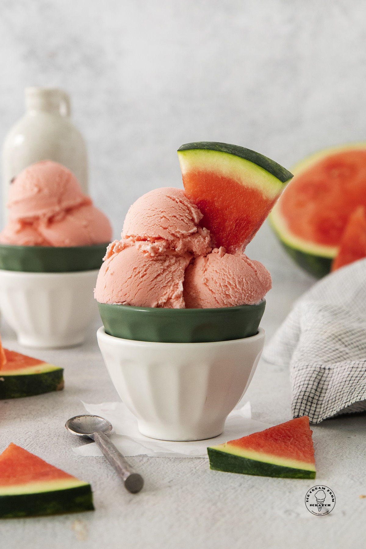 a ceramic bowl filled with scoops of homemade watermelon ice cream. Wedges of fresh watermelon are used as a garnish.