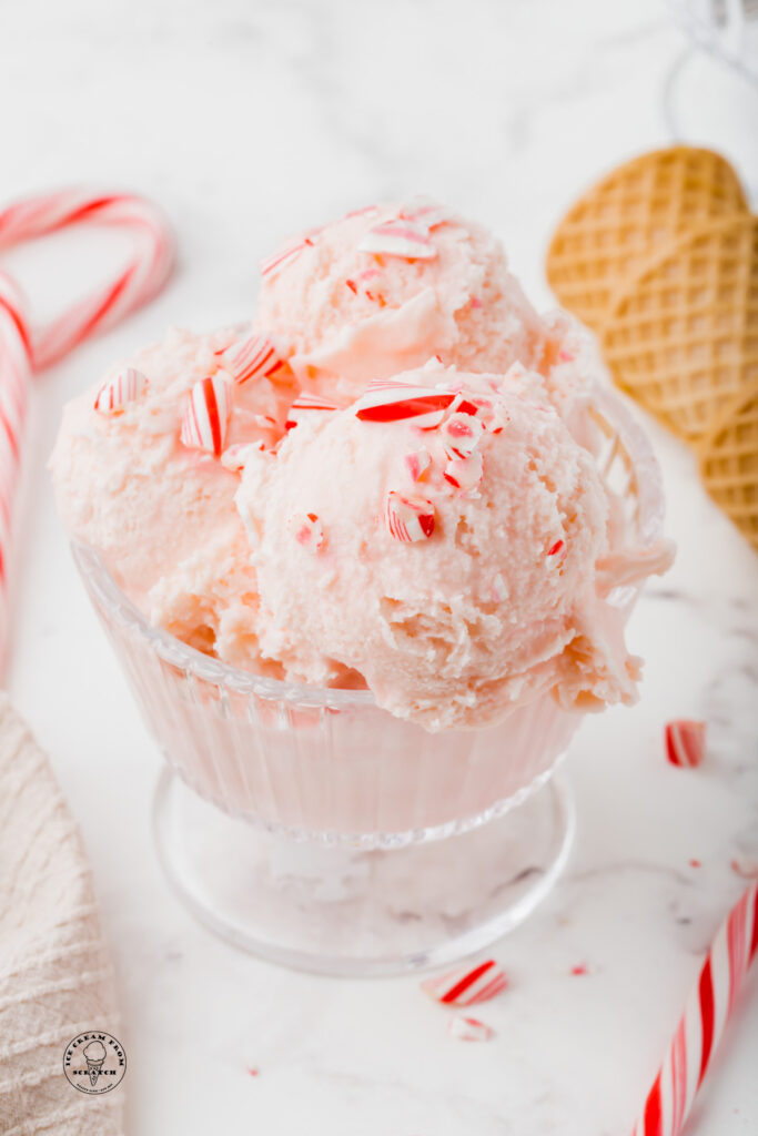 a bowl of pink candy cane ice cream topped with crushed candy cane pieces