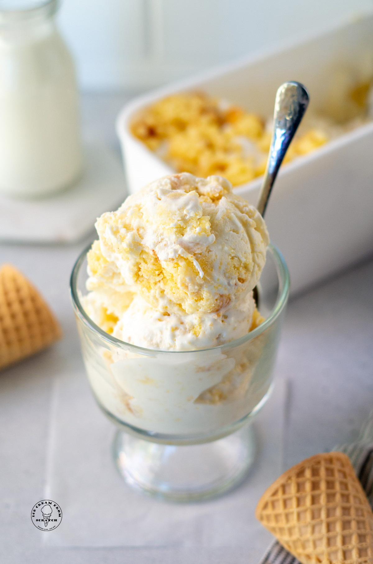 A glass dish of cornbread ice cream with a spoon in it.