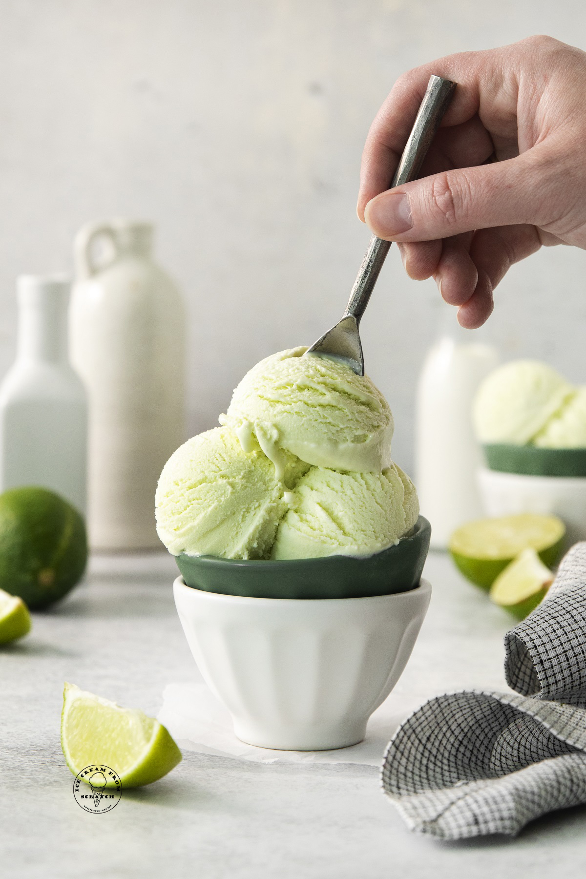 a hand using a spoon to eat a bowl of homemade lime ice cream.