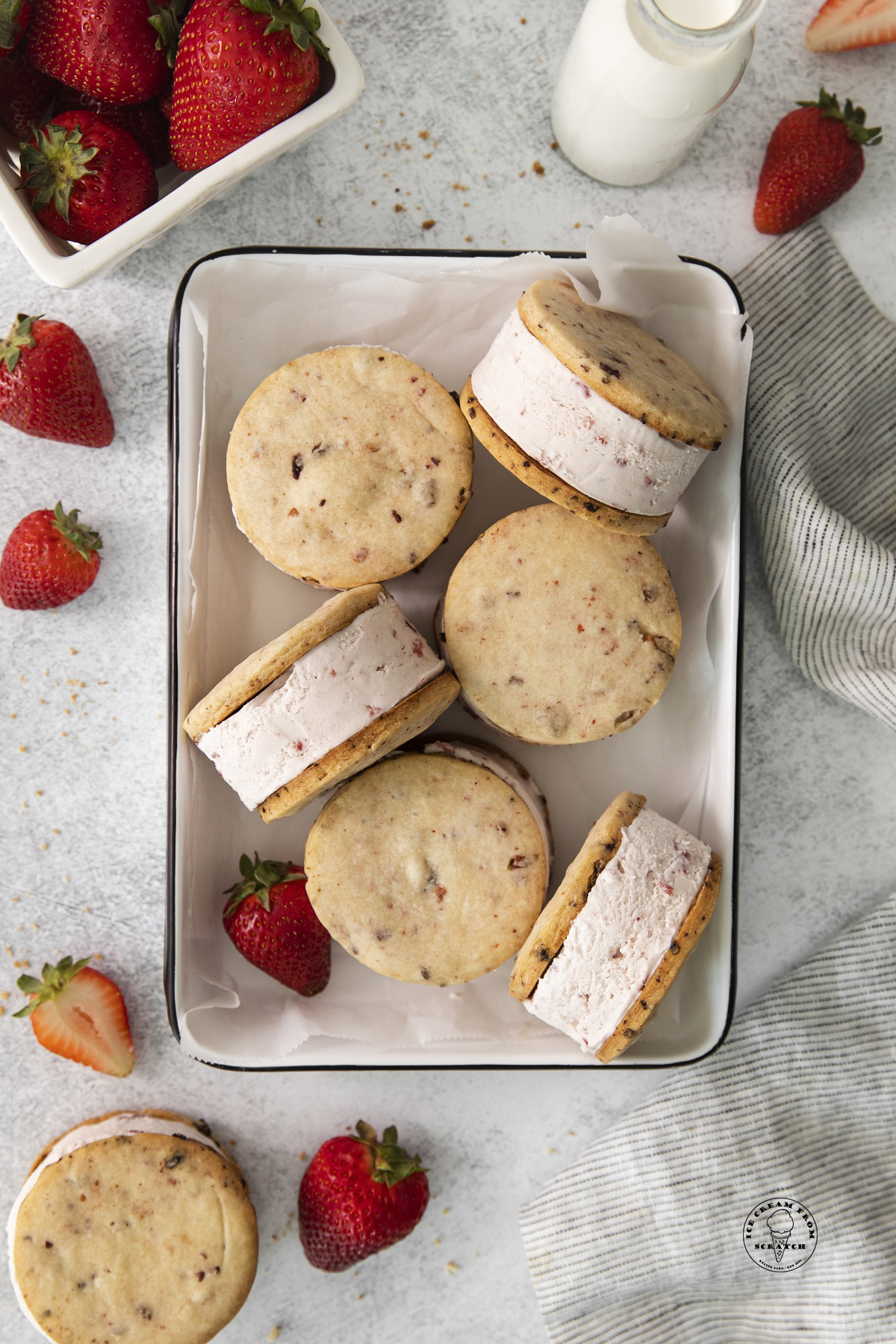 a baking dish holding six strawberry ice cream sandwiches made with strawberry shortbread cookies.