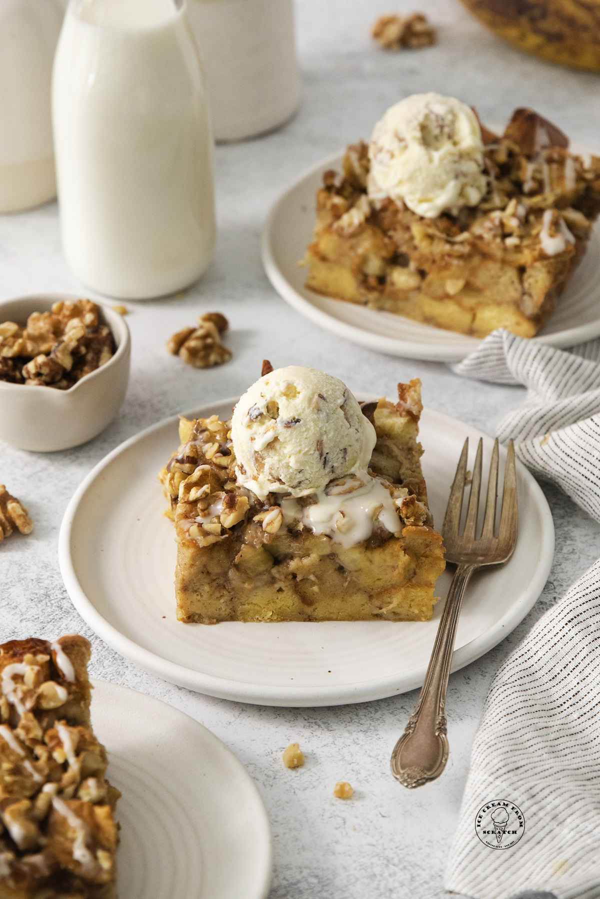 squares of Bread pudding made with bananas and nuts on dessert plates topped with ice cream