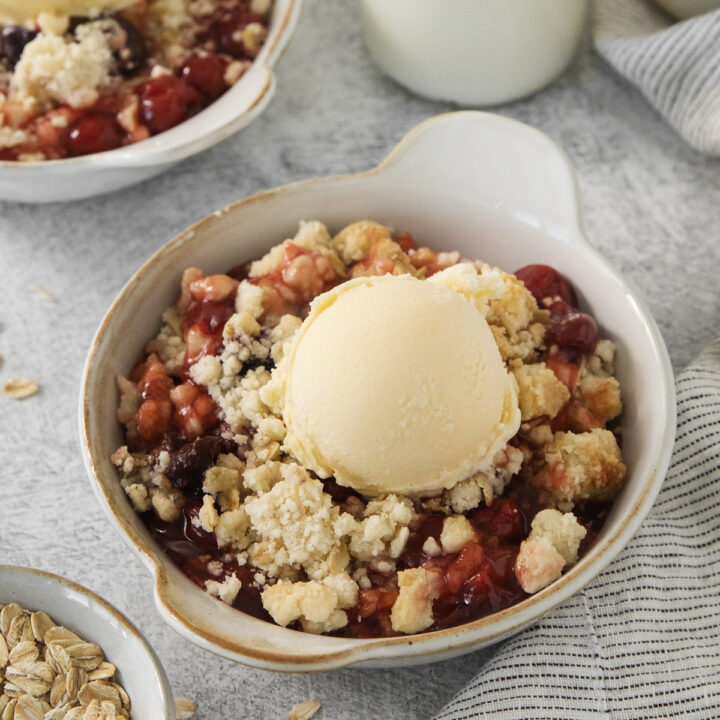 a bowl of cherry cobbler topped with vanilla ice cream.
