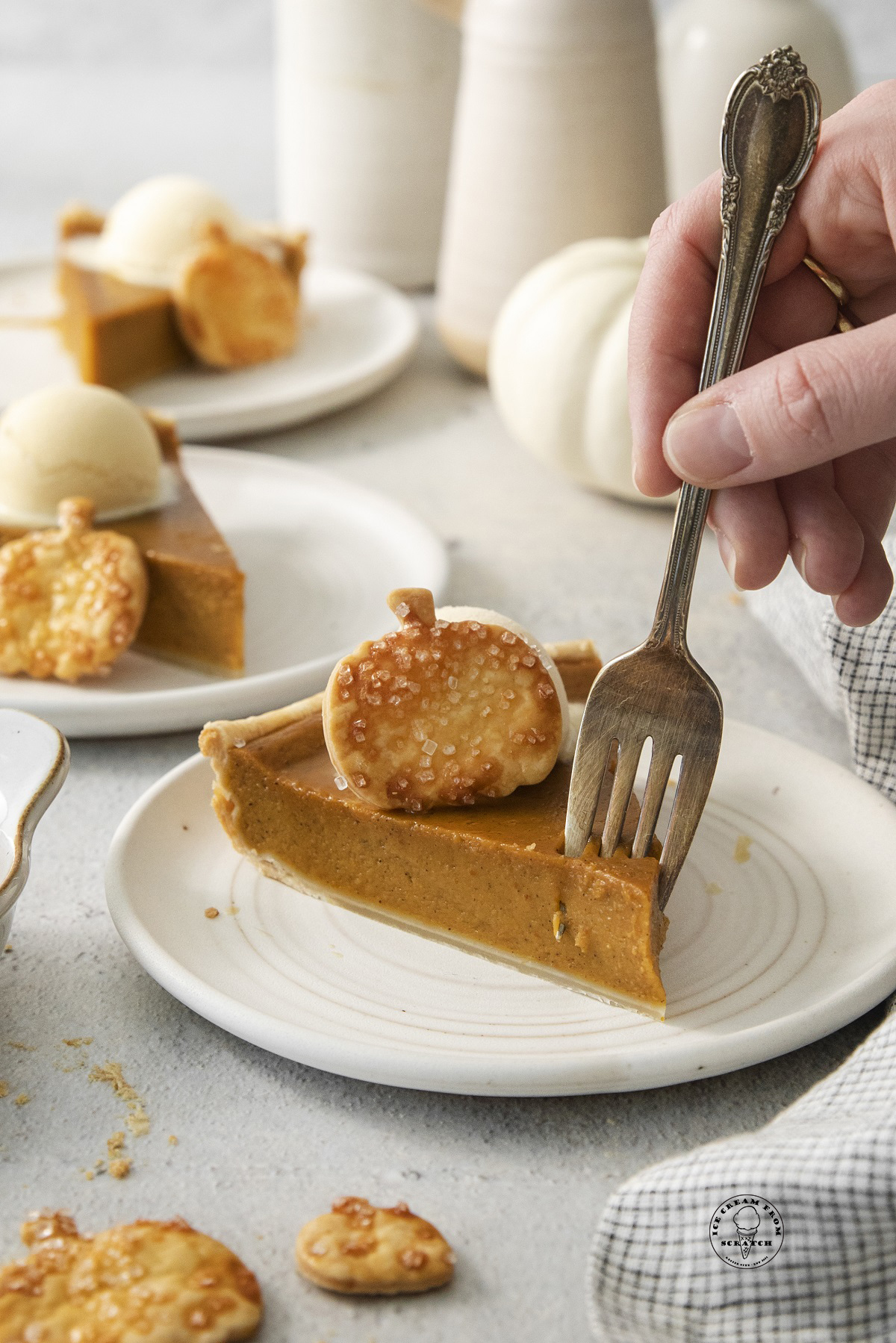 a slice of pumpkin pie with a pie crust pumpkin on top, eaten with a fork.