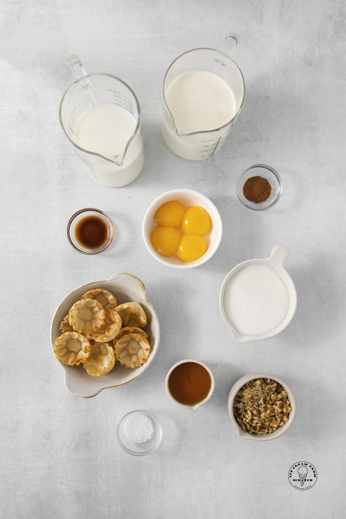 the ingredients needed to make homemade baklava ice cream, including nuts and pastry shells, all measured into separate bowls and arranged on a counter.