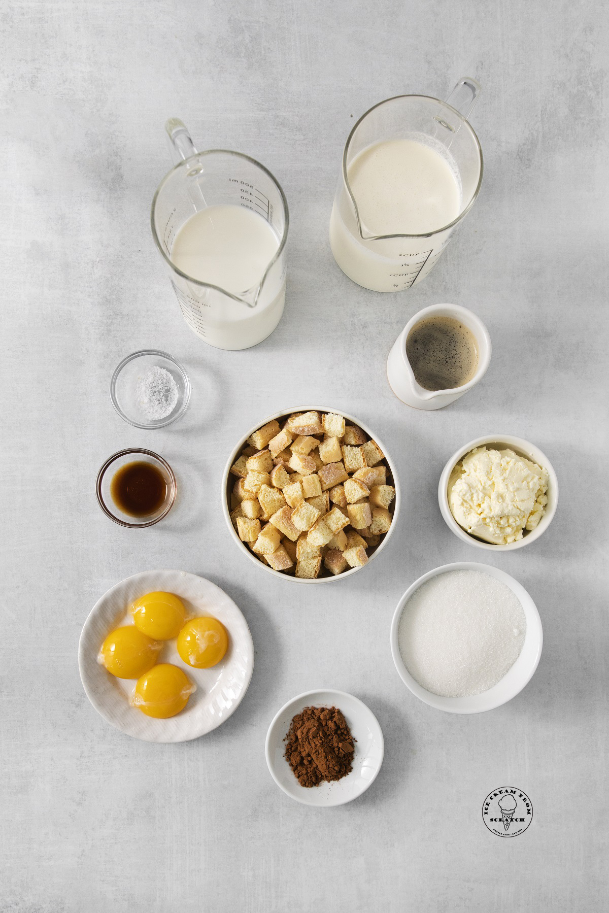 The ingredients needed to make homemade tiramisu ice cream, all in separate bowls and pitchers, arranged on a counter, and viewed from overhead.