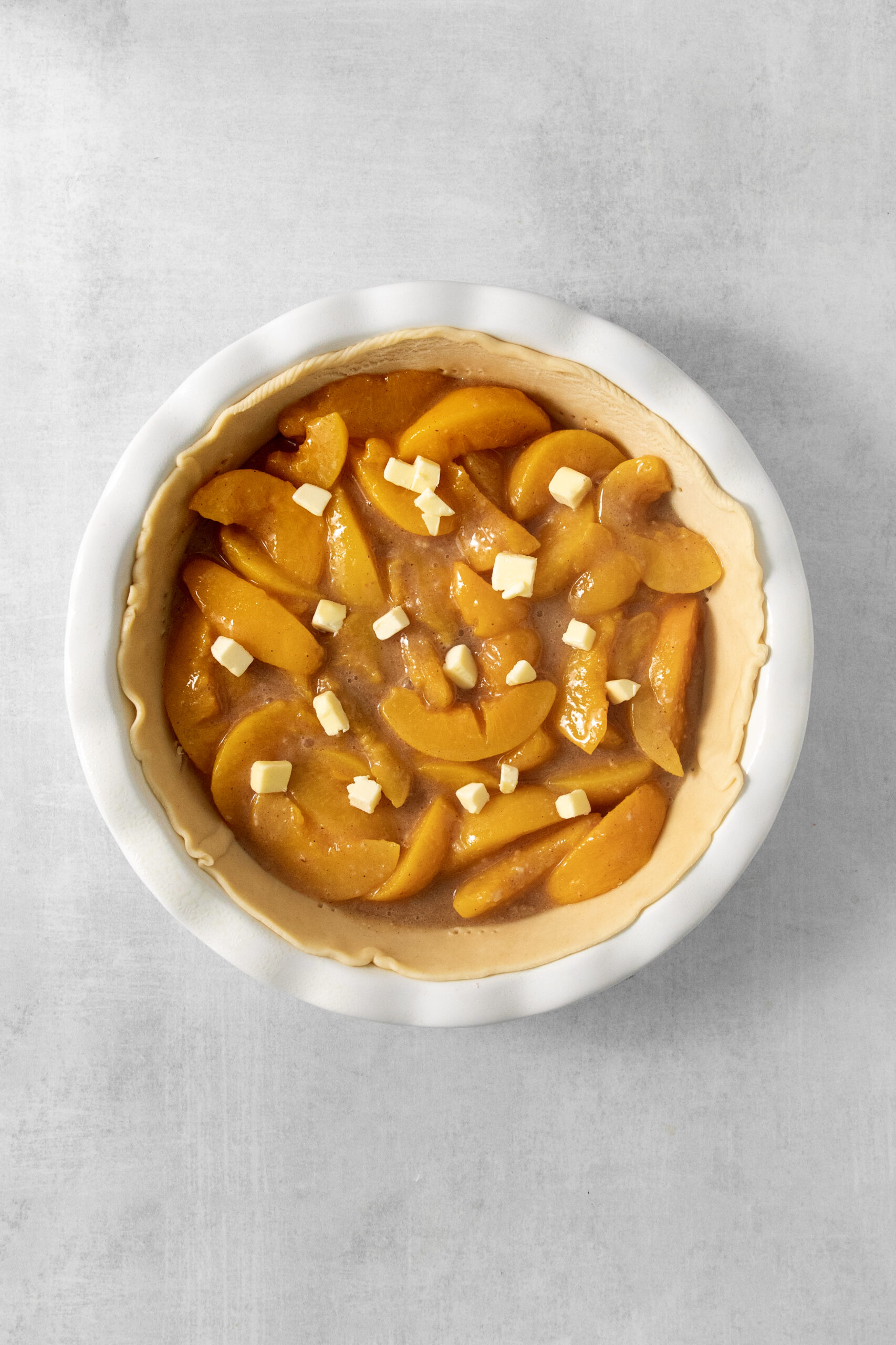 peach filling in a pie crust topped with butter pieces
