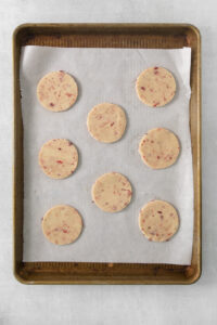 cookie dough flattened into cookie shapes on a baking sheet